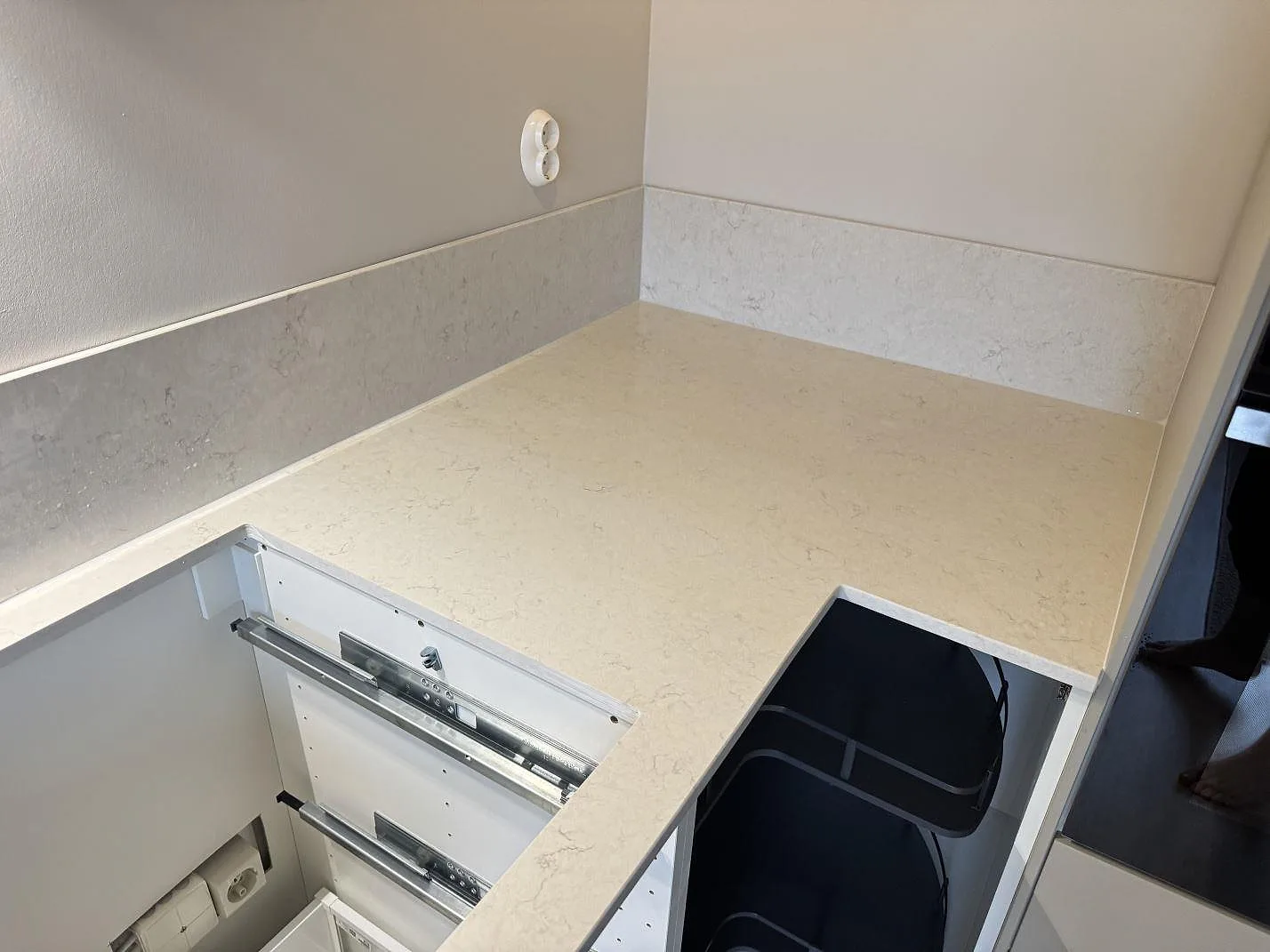 Köksbänk i Silestone Snowy Ibiza sedd över hörnet, polerad komposit med stänkkant och öppna lådstommar under montering i Laholm.