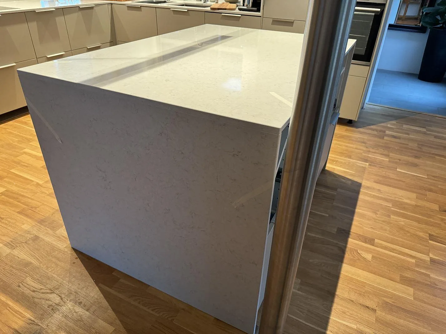 Blank köksö i vit Silestone Snowy Ibiza, polerad komposit, med omgivande köksbänkar och träinredning i Landskrona.