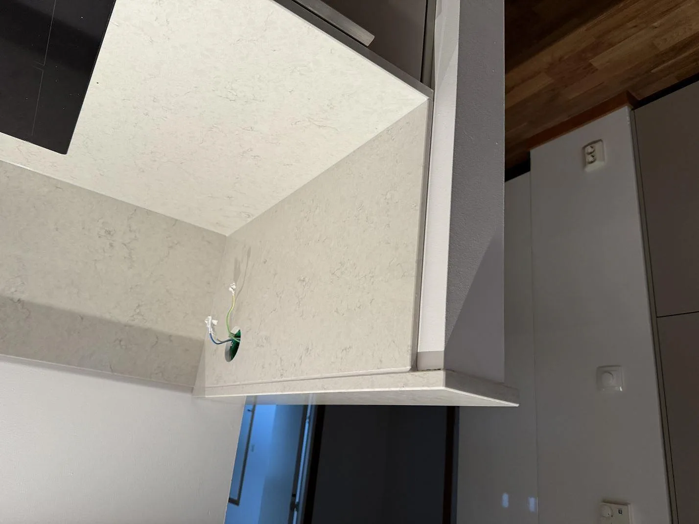 Närbild av polerad Silestone Snowy Ibiza vid induktionshäll och eluttag under montering i ett kök i Landskrona.