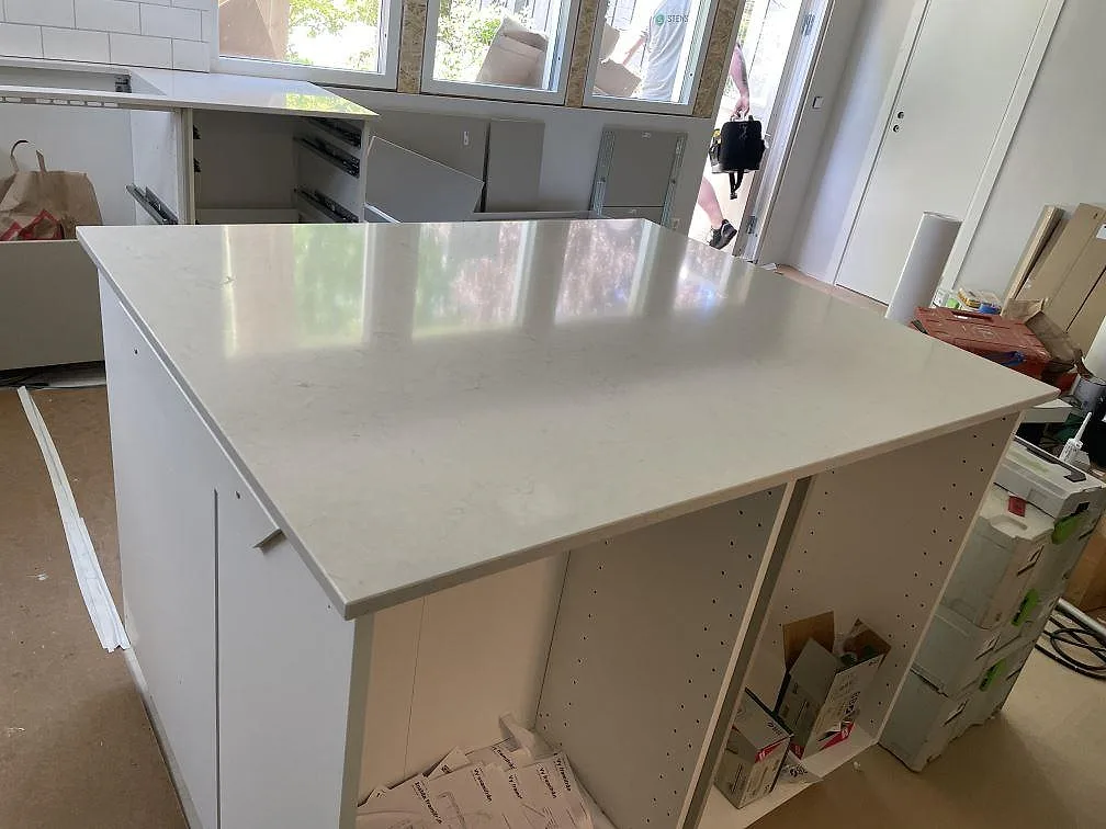 Polerad köksö i Silestone Snowy Ibiza med ljus komposityta och öppna köksstommar i Landvetter.
