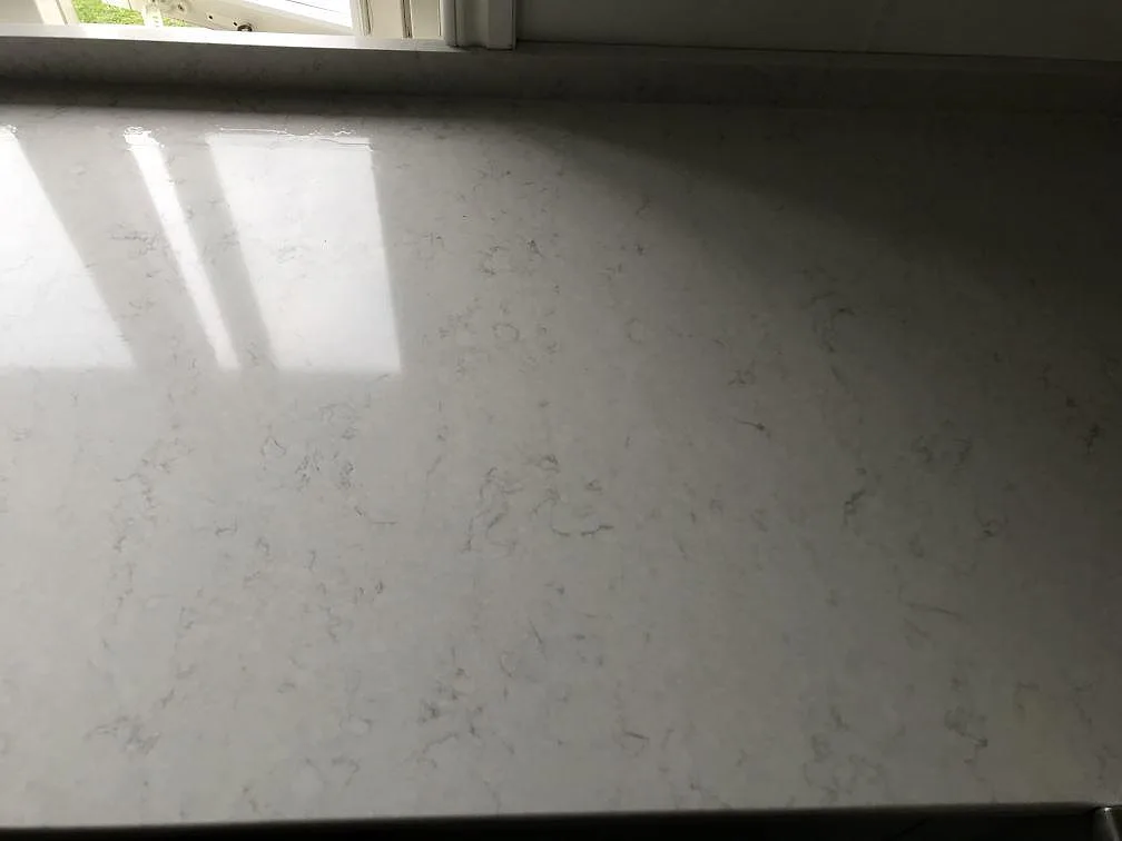 Polerad fönsterbänk i Silestone Snowy Ibiza där fönstret speglar sig i den vita kvartsytan i ett kök i Lerum.