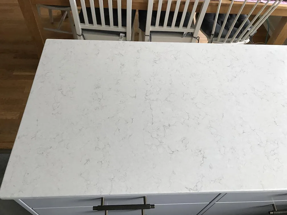 Vit Silestone Snowy Ibiza bänkskiva sedd uppifrån med köksluckans bygelhandtag i förgrunden i ett kök i Lerum.