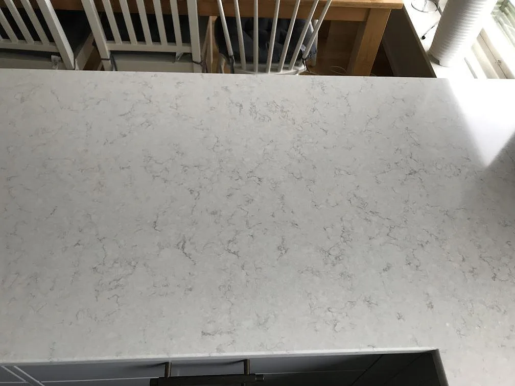 Ljus köksbänkskiva i Silestone Snowy Ibiza med mjuk grå ådring, sedd uppifrån mot matplatsen i ett kök i Lerum.