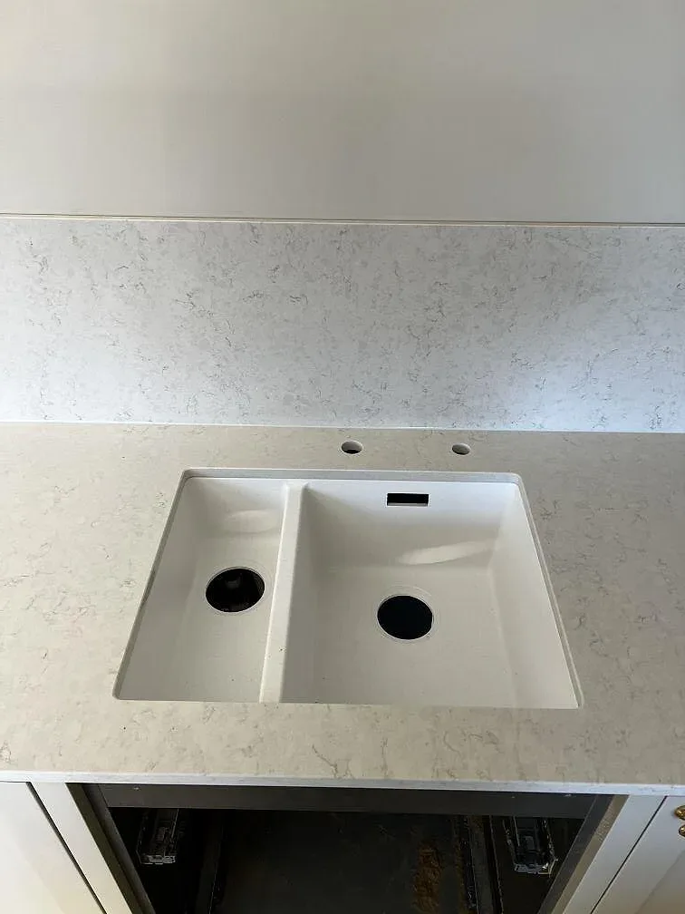 Underlimmad vit kompositdiskho med dubbla hoar i polerad Silestone Snowy Ibiza bänkskiva i ett kök i Lidköping.