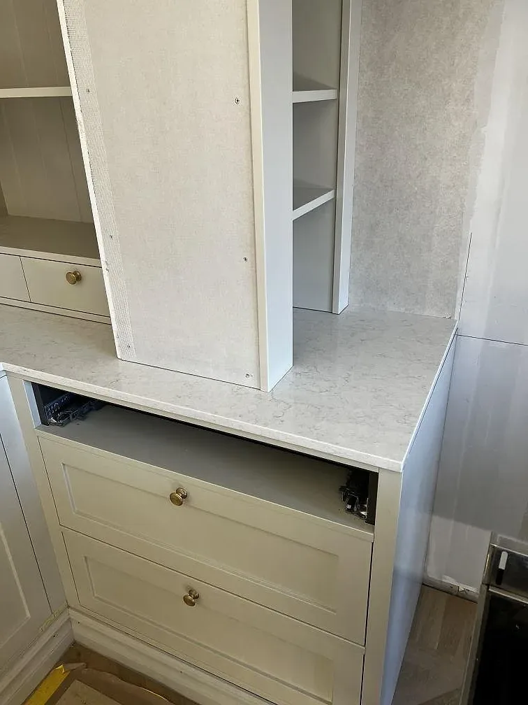 Vit Silestone Snowy Ibiza bänkskiva och stänkskydd mot krämvita köksluckor med mässingsknoppar i ett kök i Lidköping.