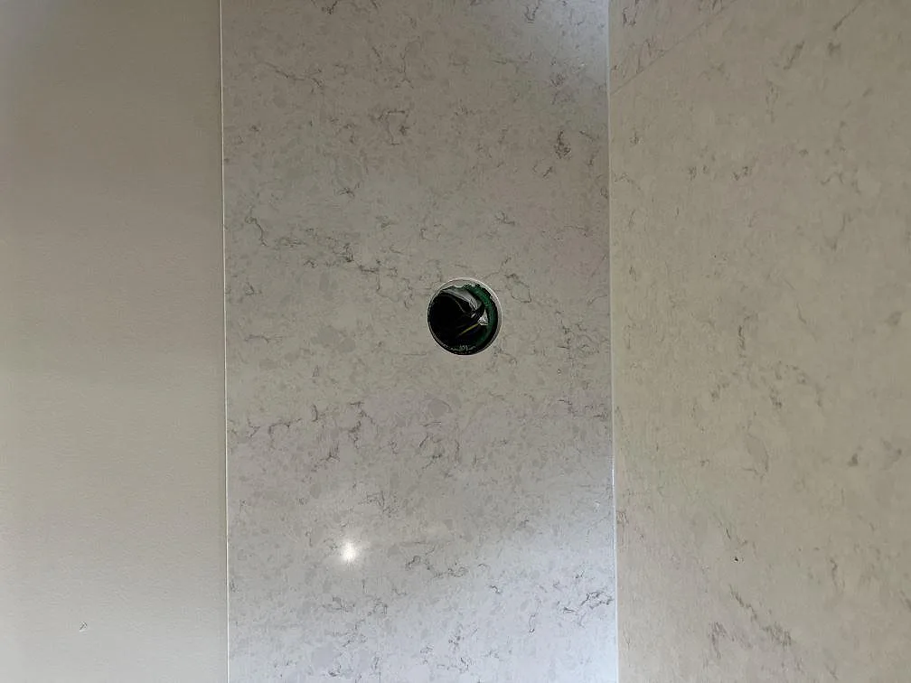 Närbild på polerad vit Silestone Snowy Ibiza med mjuk grå ådring och uppvikt stänkskydd i ett kök i Lidköping.