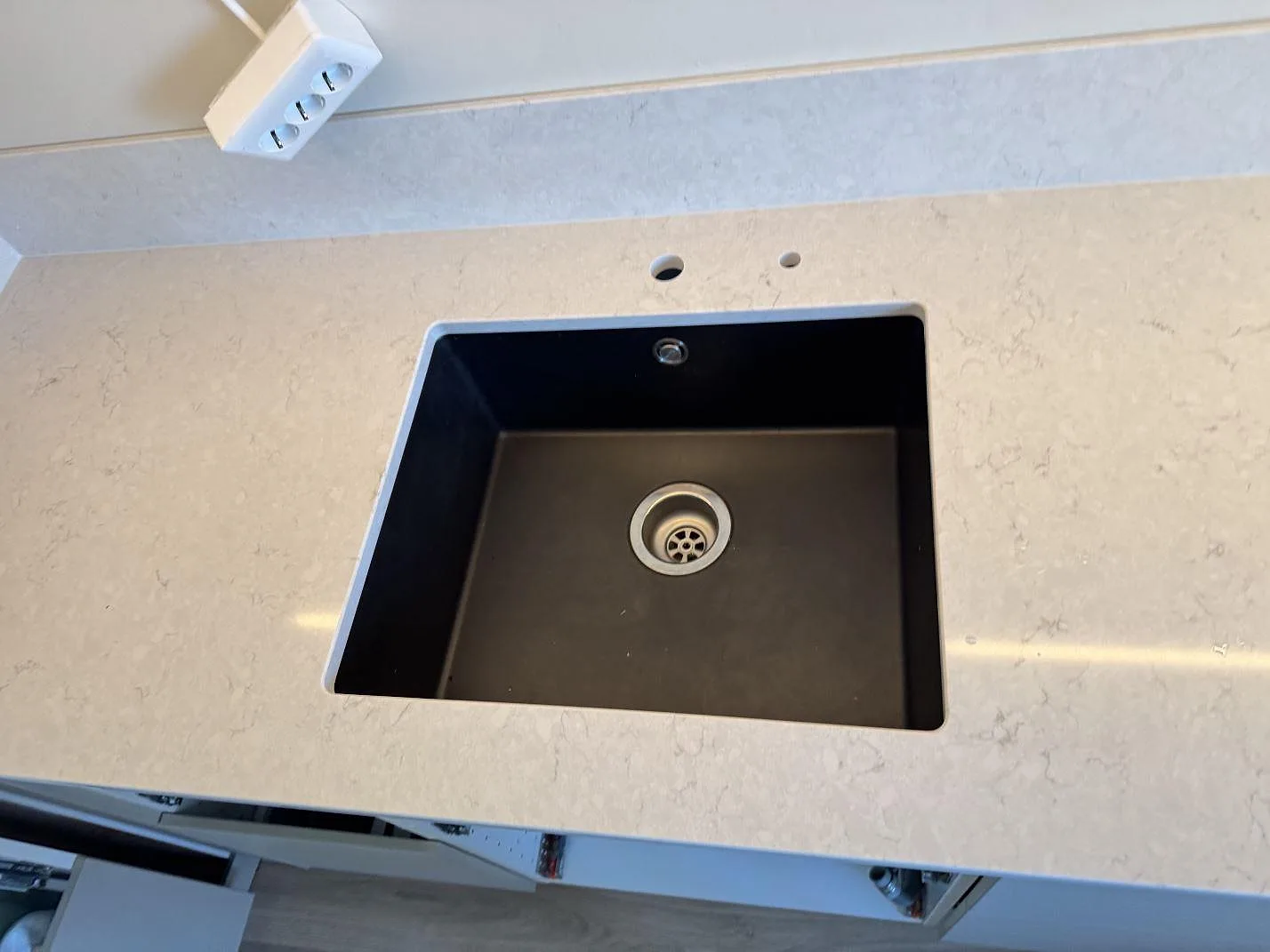 Närbild på svart diskho monterad under en polerad Silestone Snowy Ibiza bänkskiva med stänkskydd i Lidköping.