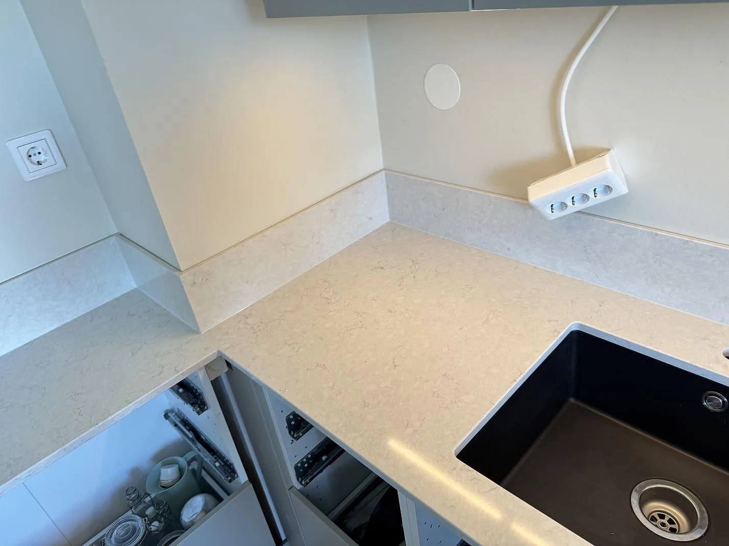 Hörn av köksbänkskiva i Silestone Snowy Ibiza med svart diskho och 12 mm stänkskydd under montering i Lidköping.