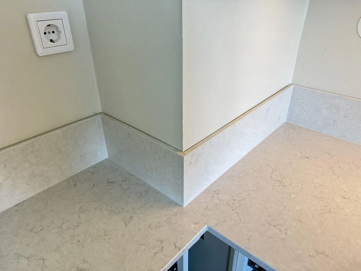 Polerad Silestone Snowy Ibiza köksbänk med 12 mm stänkskydd och öppen skåpstomme under montering i Lidköping.