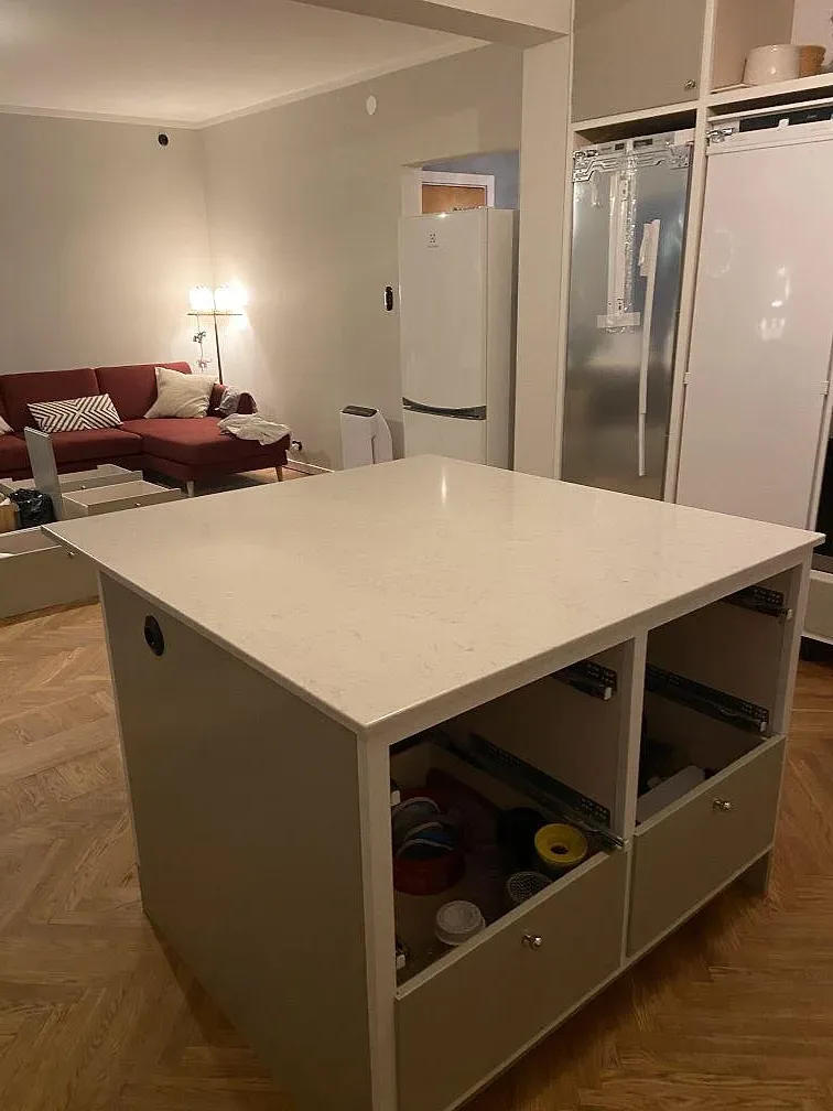 Vit Silestone Snowy Ibiza köksö med öppna stommar och fiskbensparkett under montering i ett kök i Limhamn.