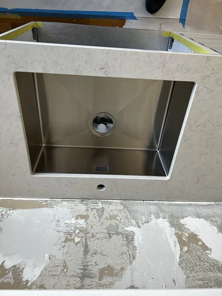 Koksbankskiva i vit Silestone Snowy Ibiza, polerad, med underlimmad rostfri diskho och kranhal i ett kok i Limhamn.