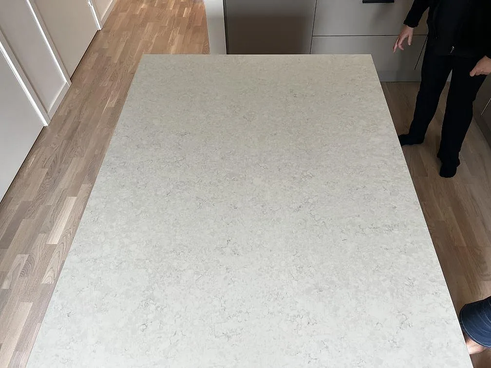 Installerad köksö i polerad Silestone Snowy Ibiza med ljus ådring och träinredning runt arbetsytan i Limhamn.