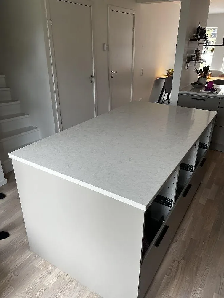 Köksö eller halvö med neddragen gavelsida i vit polerad Silestone Snowy Ibiza, 30 mm komposit, i ett kök i Limhamn.