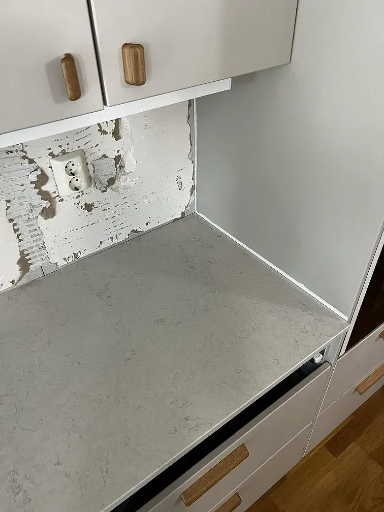Hörnparti av ljus Silestone Snowy Ibiza i polerad komposit med vita köksskåp i Limhamn.