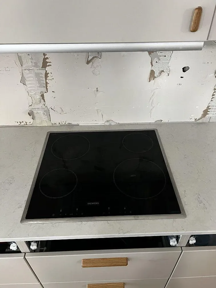 Svart induktionshäll infälld i polerad Silestone Snowy Ibiza med väggparti under renovering i Limhamn.