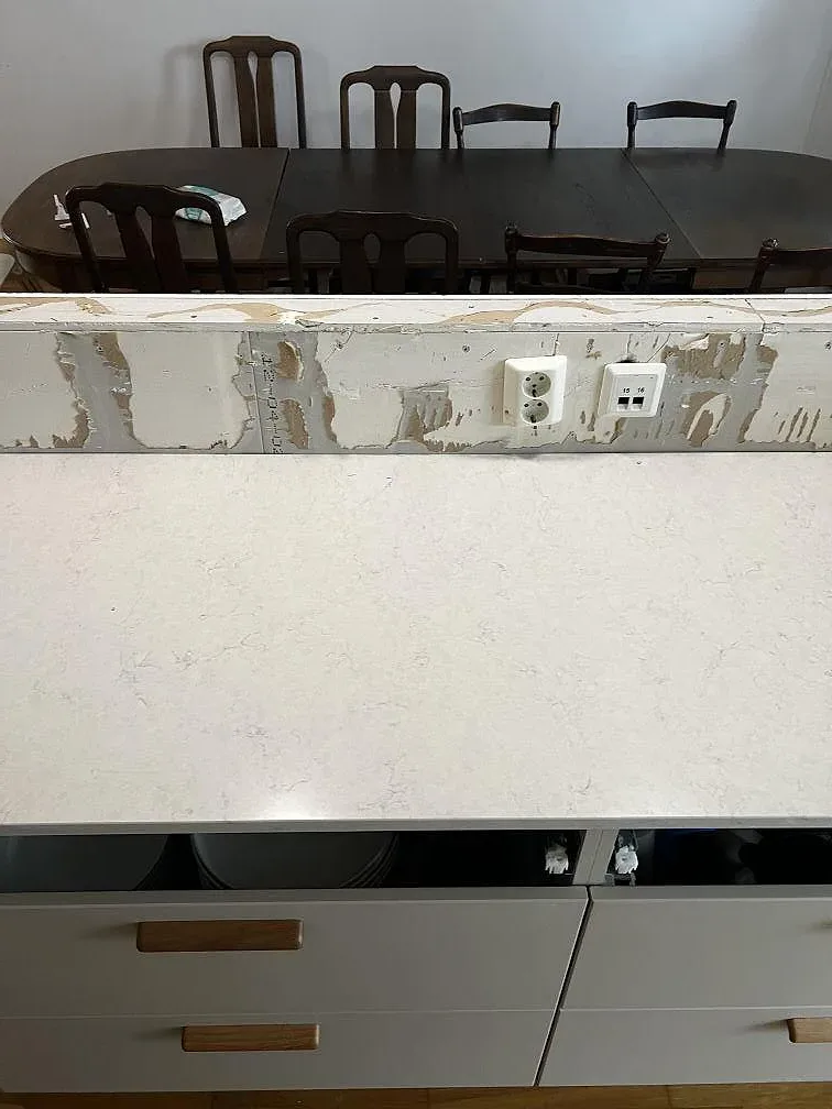 Polerad köksbänkskiva i Silestone Snowy Ibiza sedd över halvön med matplatsen bakom i Limhamn.