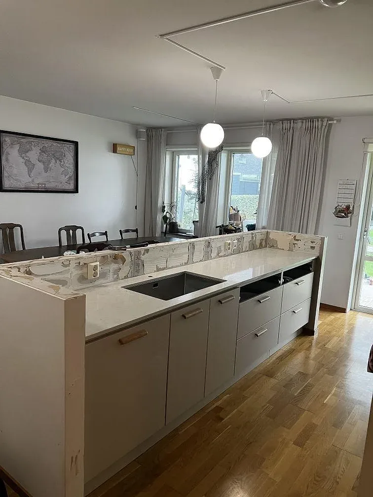Köksbänkskiva i vit polerad Silestone Snowy Ibiza med underlimmad rostfri diskho och halvö i ett kök i Limhamn.