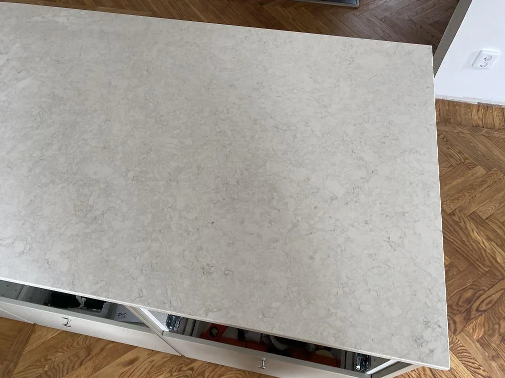 Hörn och yta på köksö i polerad Silestone Snowy Ibiza, monterad på vita köksstommar i Limhamn.