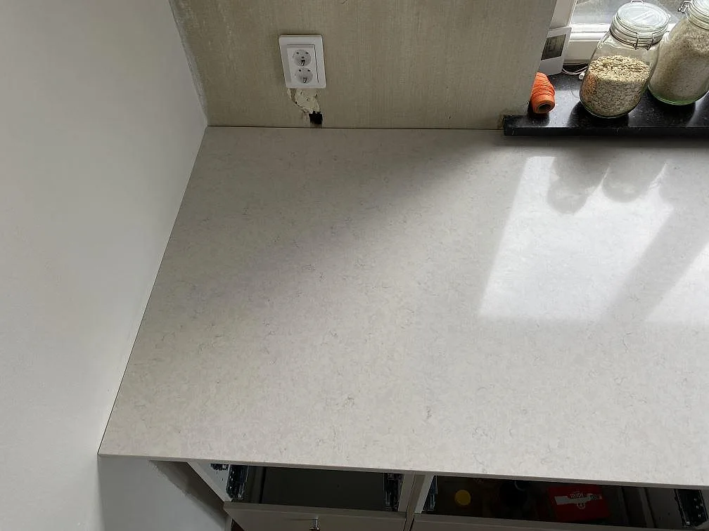 Bänkskiva i polerad Silestone Snowy Ibiza vid fönster och vägg, med ljus kvartskomposit i köket i Limhamn.