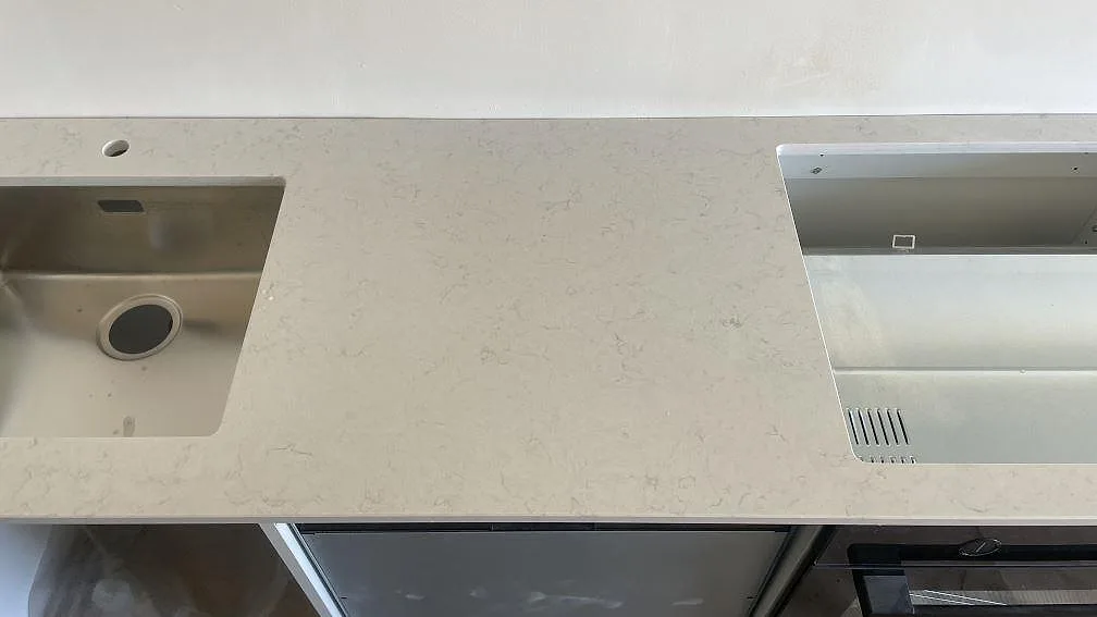 Polerad Silestone Snowy Ibiza-köksbänkskiva i Limhamn med rostfri diskho till vänster och förberett hällurtag till höger.