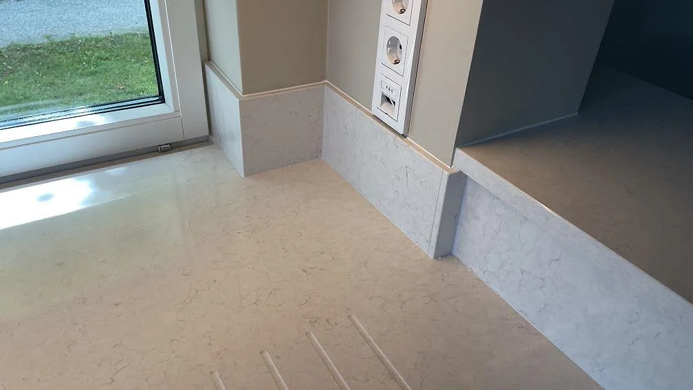 Fönsternisch och stänkpartier i polerad Silestone Snowy Ibiza över en ljus köksbänkskiva i Limhamn.