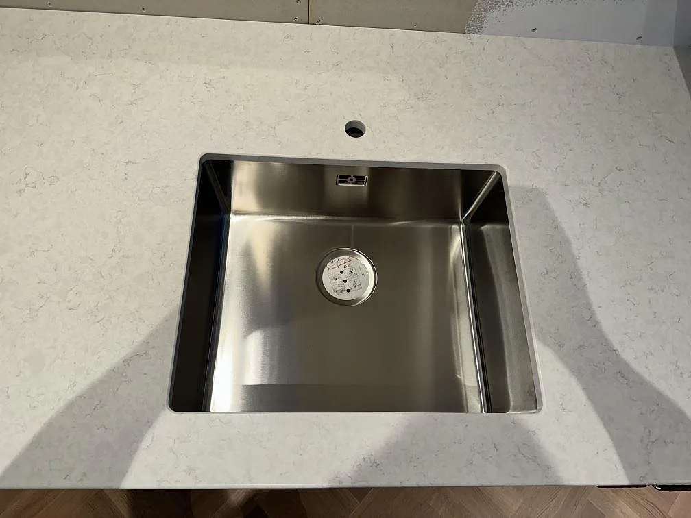 Diskho i rostfritt stål monterad i polerad Silestone Snowy Ibiza, med blandarhål och ljus kvartskomposit i Lindome.
