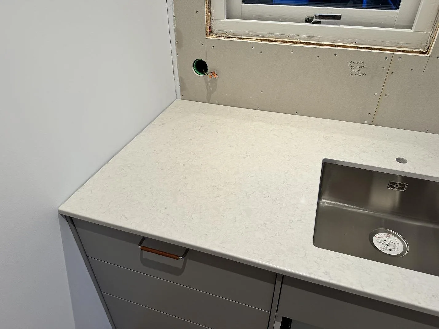 Polerad Silestone Snowy Ibiza som köksbänkskiva vid fönster, med rostfri diskho och ljus komposityta i Lindome.