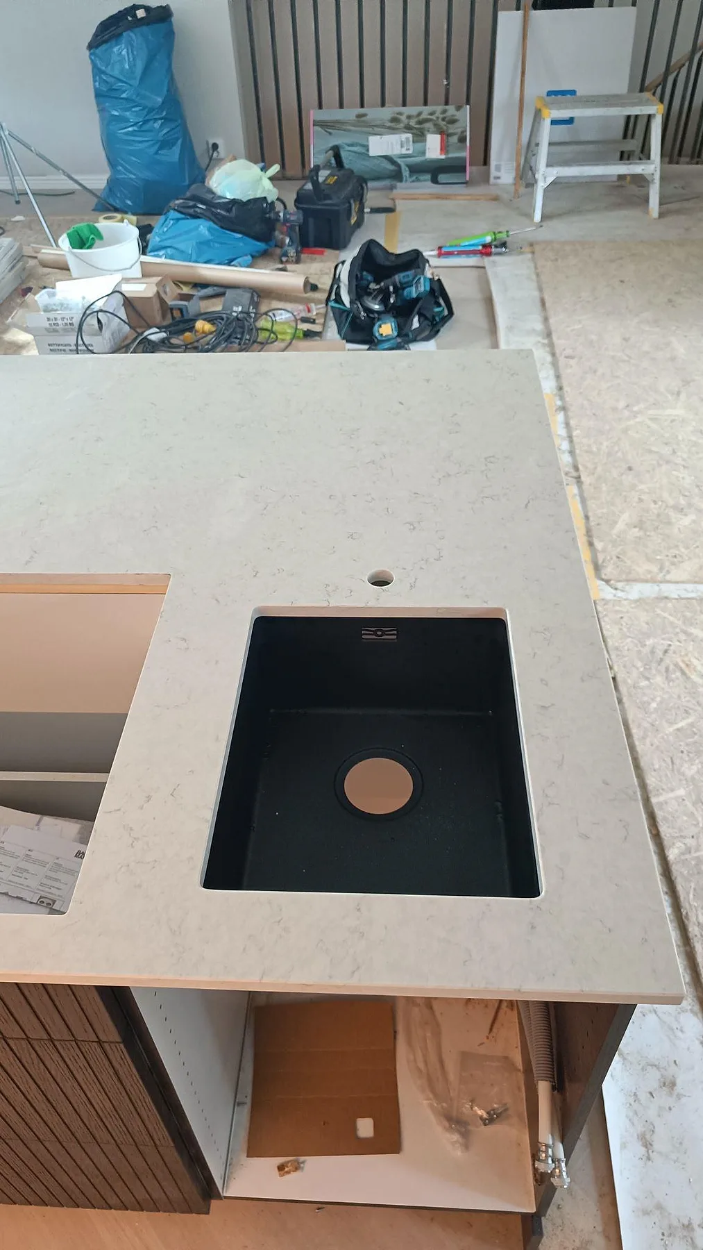 Närbild av svart diskho i polerad Silestone Snowy Ibiza på en stor köksö med ljus kvartskomposit i Löddeköpinge.