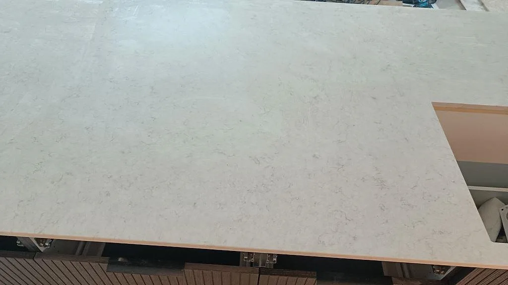 Ytdetalj av polerad Silestone Snowy Ibiza, ljus kvartskomposit med grå ådring på köksö i Löddeköpinge.