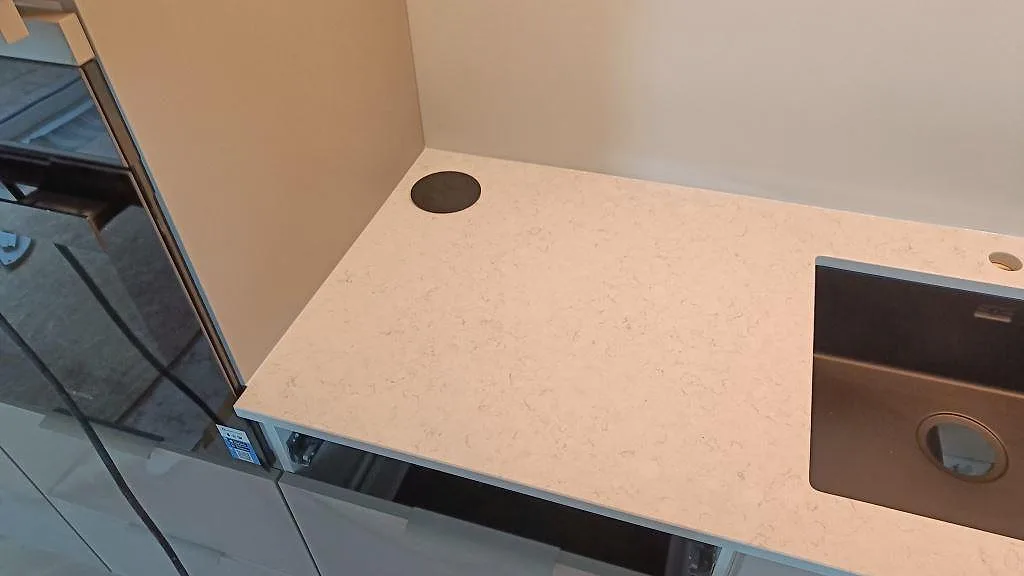 Bakre bänkskiva i polerad Silestone Snowy Ibiza med svart diskho och blandarhål i ett kök i Löddeköpinge.