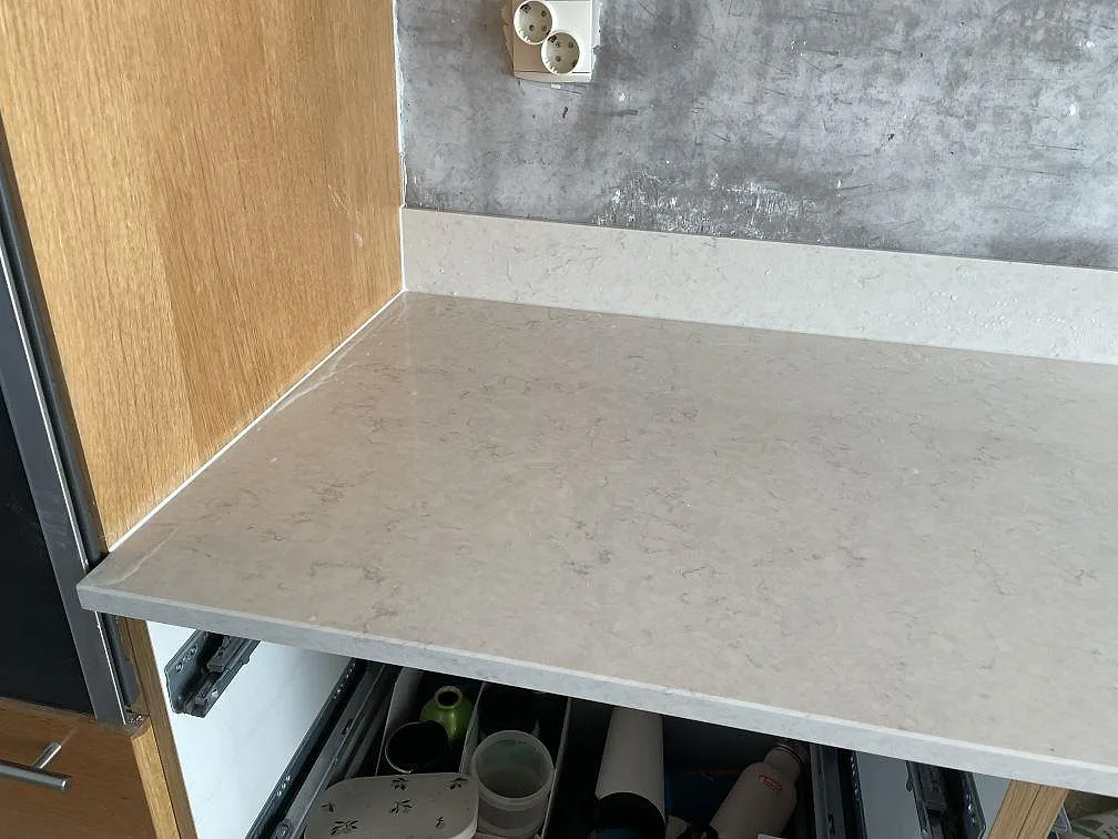 Hörndel av köksbänkskiva i Silestone Snowy Ibiza, polerad, mot träinredning och betongliknande vägg i Lomma.