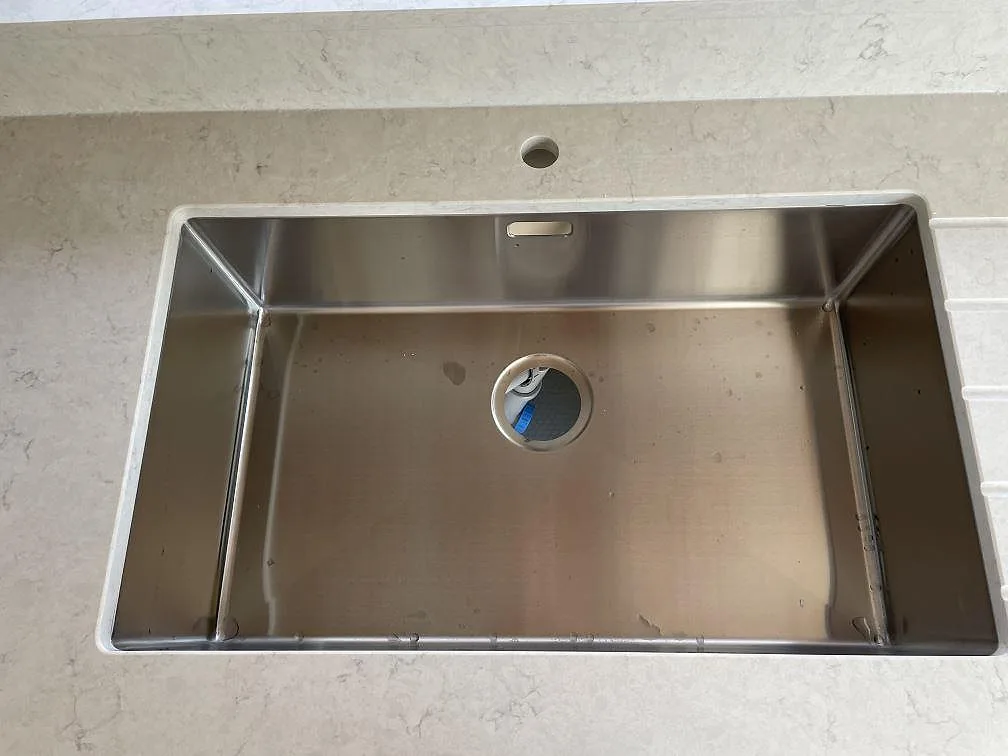 Rostfri underlimmad diskho monterad i polerad Silestone Snowy Ibiza med ljus ådring och stänkkant i Lomma.