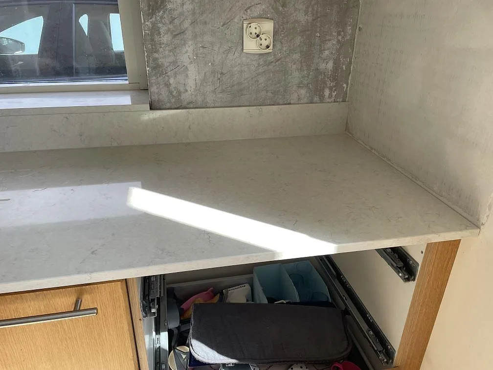 Polerad Silestone Snowy Ibiza som installerad köksbänkskiva vid fönster, med ljus ådring och stänkkant i Lomma.