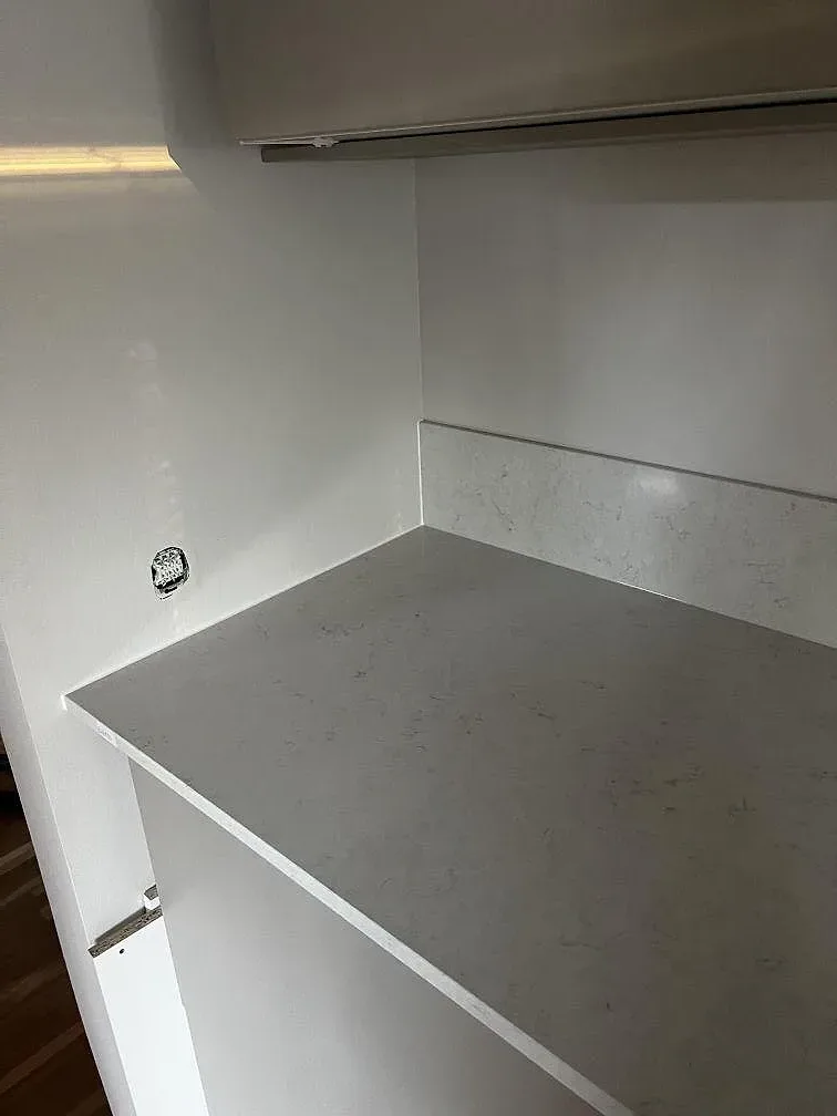 Hörnsektion i polerad Silestone Snowy Ibiza med ljus stänkkant och vit köksinredning under montering i Lomma.