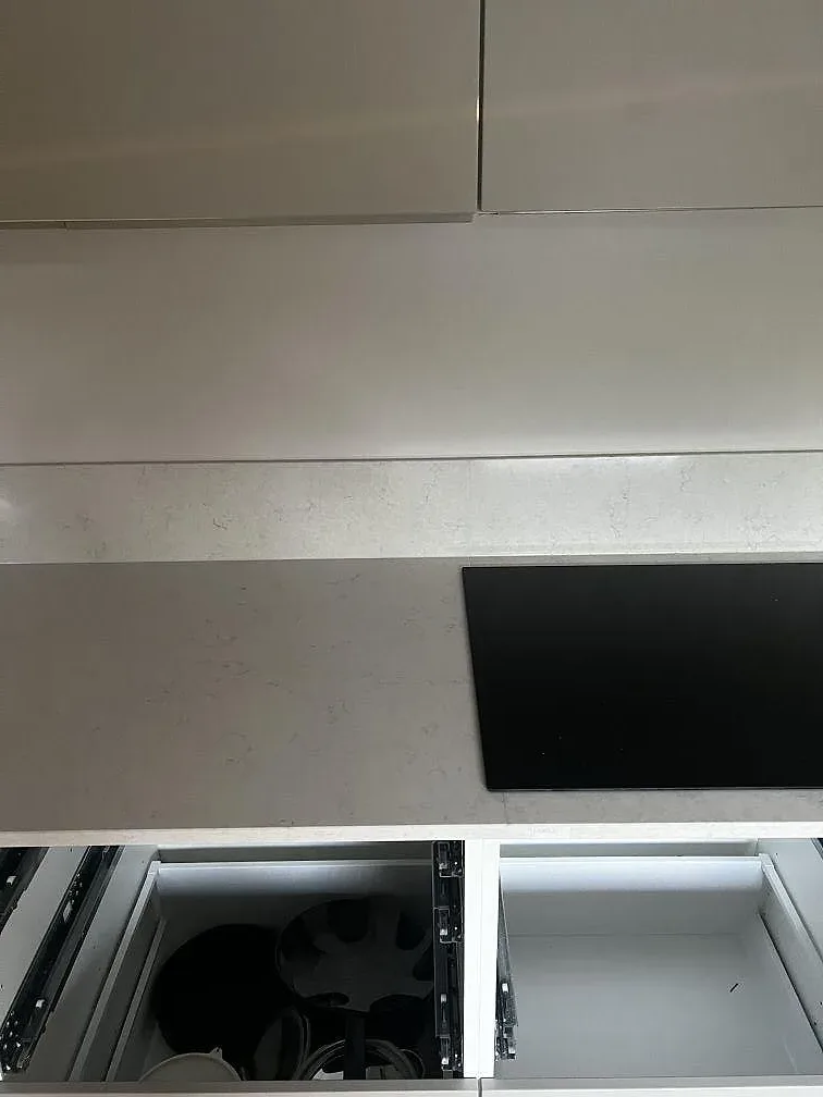 Närbild på polerad Silestone Snowy Ibiza komposit runt hällzonen i ett vitt kök under montering i Lomma.