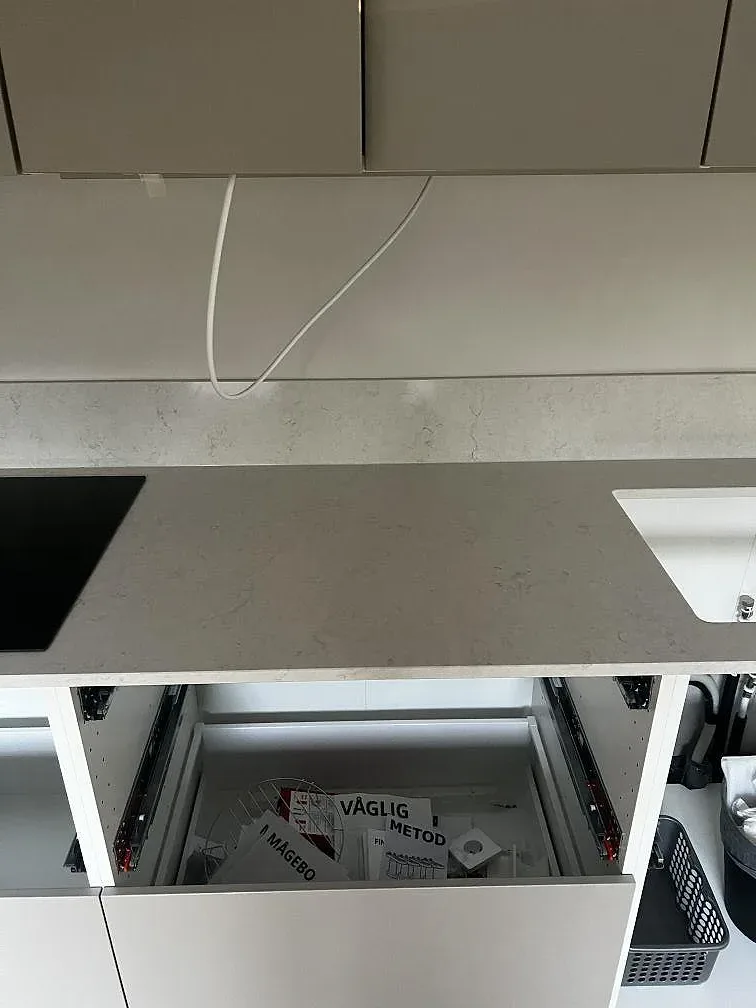 Köksbänkskiva i polerad Silestone Snowy Ibiza med diskho- och hällzoner längs en vit skåprad i Lomma.