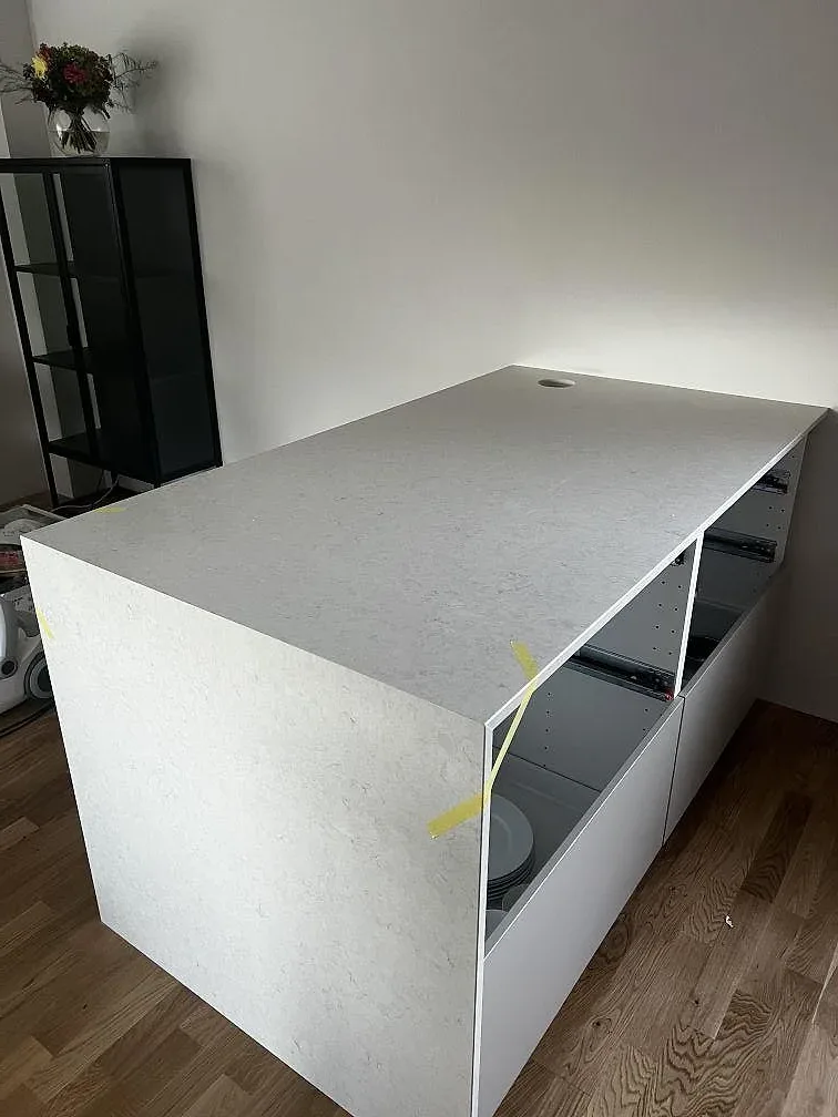Gavelsida och bänkskiva i polerad Silestone Snowy Ibiza komposit med trägolv och vita köksstommar i Lomma.
