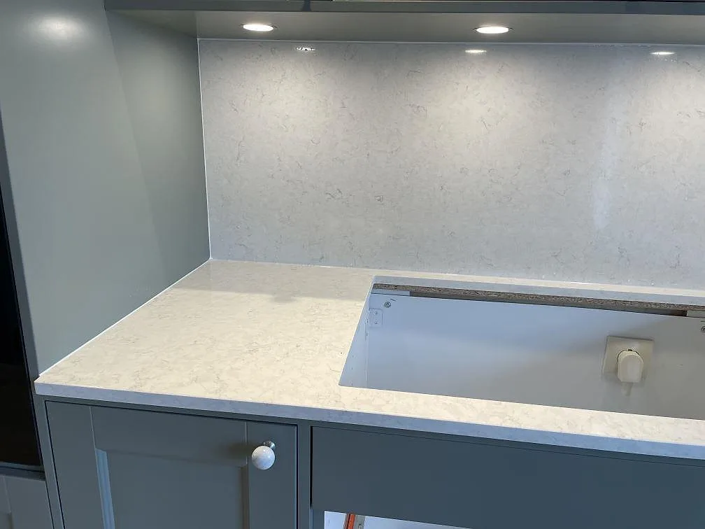Köksbänkskiva i polerad Silestone Snowy Ibiza komposit med diskho under montering och grå fronter i Ludvigsborg.