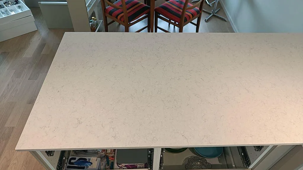 Ovanifrån på en köksö i polerad Silestone Snowy Ibiza i Lund med fin grå ådring i den vita kompositytan.