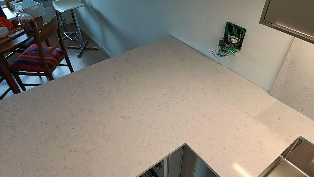 Köksö i vit Silestone Snowy Ibiza sedd ovanifrån i ett kök i Lund, med diskret grå ådring i den polerade ytan.