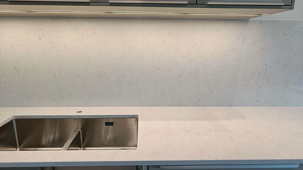 Vit Silestone Snowy Ibiza bänkskiva i Lund med underlimmad rostfri dubbelho och separat hål för köksblandare, mot en stänkvägg i kompositsten.