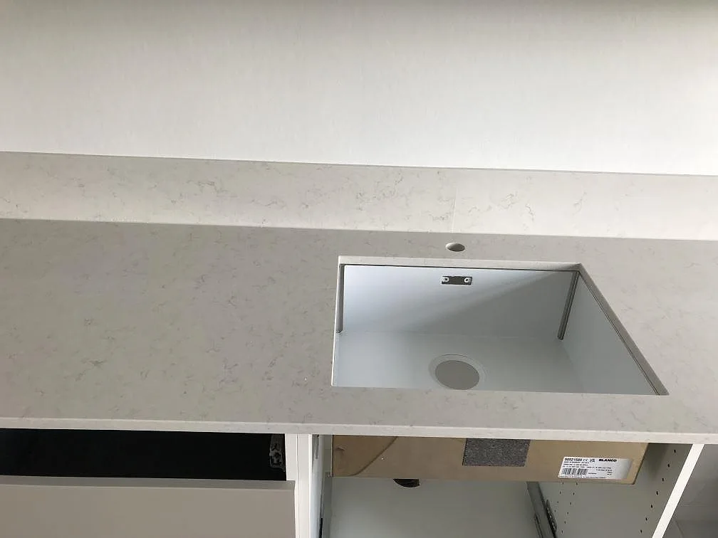 Underlimmad rostfri Blanco-diskho i en köksbänkskiva av Silestone Snowy Ibiza med separat borrat kranhål, i ett kök i Lund.