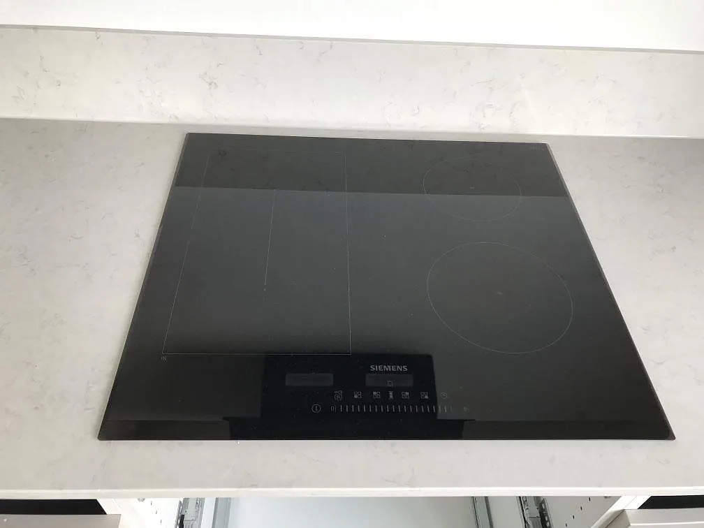 Infälld Siemens induktionshäll i en köksbänkskiva av vit Silestone Snowy Ibiza i ett kök i Lund.