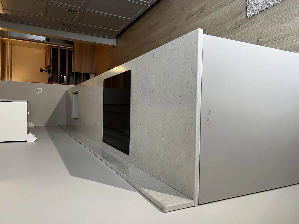 Köksbänkskiva i vit Silestone Snowy Ibiza, polerad, på en köksö med nedsänkt induktionshäll och stänkskydd i samma sten, fotograferad under montering i ett kök i Lund.