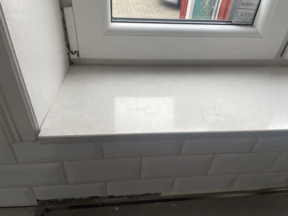 Fönsterbänk i vit Silestone Snowy Ibiza, polerad, mot vitt fasat kakel i ett kök i Lund.