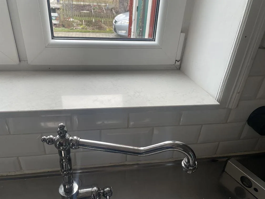 Polerad fönsterbänk i Silestone Snowy Ibiza med rostfri diskho och förkromad blandare i ett kök i Lund.