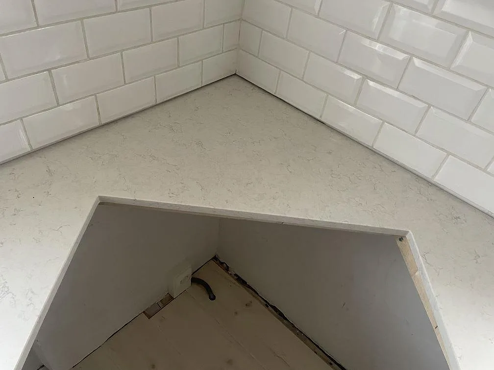 Underlimmad urtagning i en bänkskiva av Silestone Snowy Ibiza mot vitt kakel i ett kök i Lund.