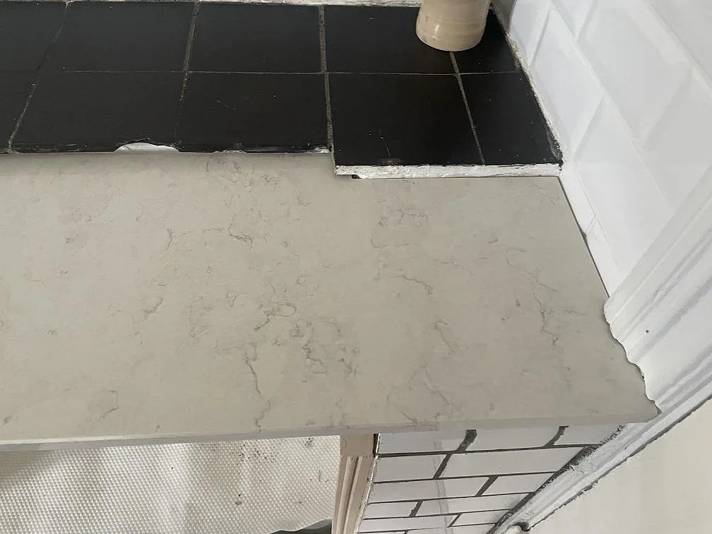 Köksbänkskiva i Silestone Snowy Ibiza möter en svart klinkeryta i ett kök i Lund, med vitt fasat kakel som stänkskydd.