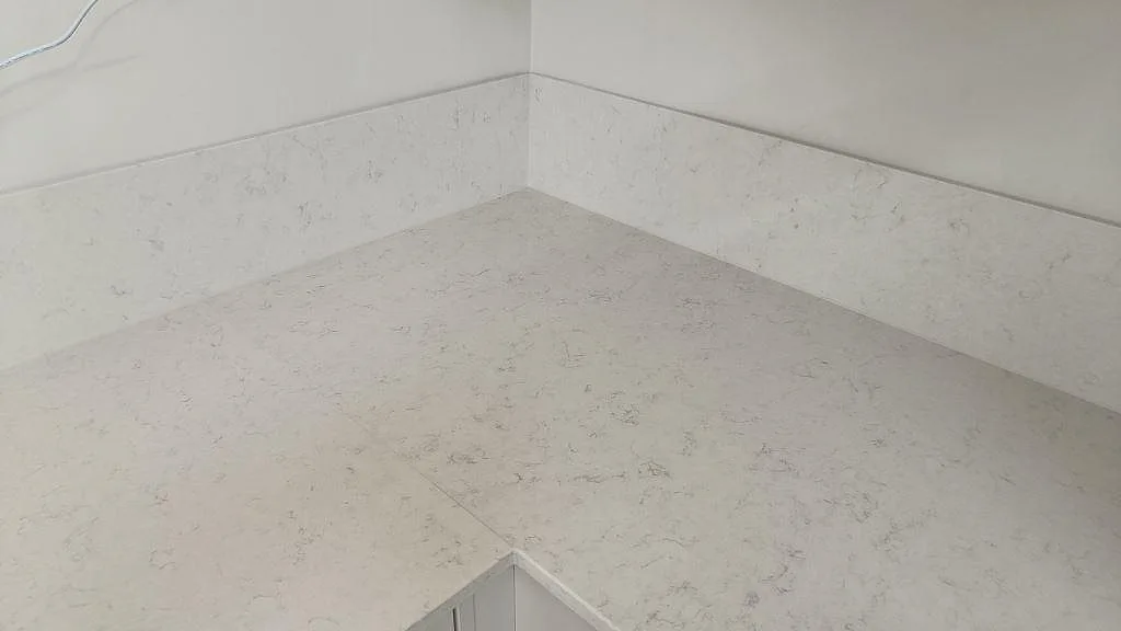 Hörnparti med polerad Silestone Snowy Ibiza bänkskiva och matchande stänkskydd i ett kök i Lund.