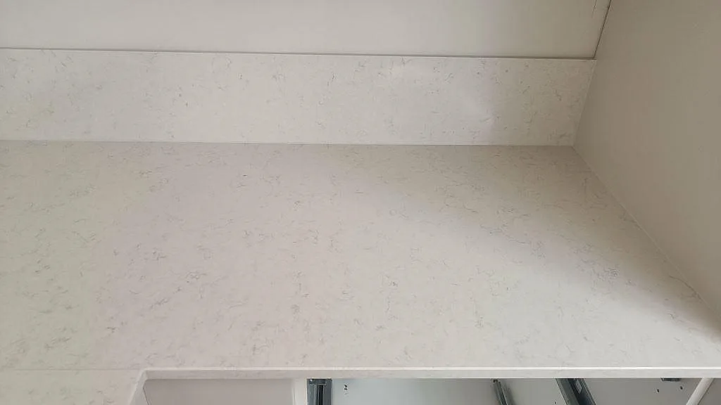 Närbild av vit Silestone Snowy Ibiza som polerad köksbänkskiva med stänkskydd över öppna stommar i Lund.